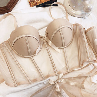 Flat lay of the Shannon bra and pantie set in beige on a white sheet with accessories in the background