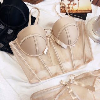 Flat lay of the Shannon bra and pantie set in beige and black on a white sheet with accessories in the background