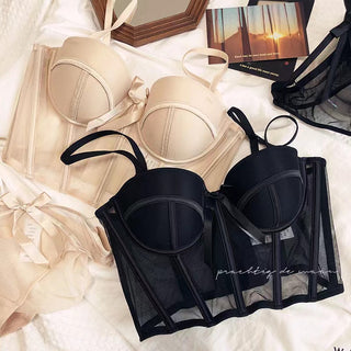 Flat lay of the Shannon bra and pantie set in beige and black on a white sheet with accessories in the background