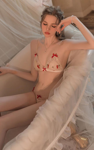 Model wearing Sakura bra set in white with cherry pattern posing sat in a bath tub